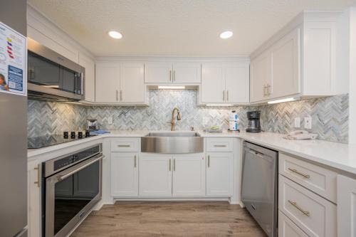 a kitchen with white cabinets and a sink at Phoenix VI 6906 in Orange Beach
