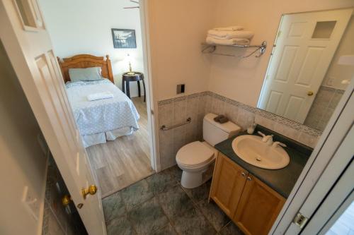 a bathroom with a toilet and a sink and a bed at Sonora Desert Inn in Osoyoos