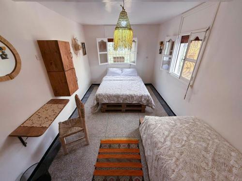 a bedroom with two beds and a chair and a chandelier at Jurassic Surf House Anza in Agadir