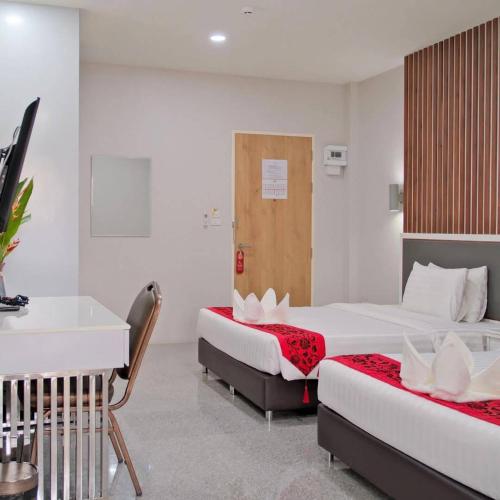 a hotel room with two beds and a desk at โกลเด้นแลนด์รีสอร์ท in Ban Dan Kwian