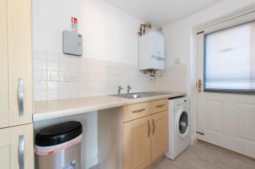 a kitchen with a sink and a washing machine at Stunning 5 bedroom detached house in Hornchurch in Romford
