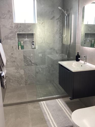 a bathroom with a shower and a sink at Harbourview Penthouse Apartment in Whitianga