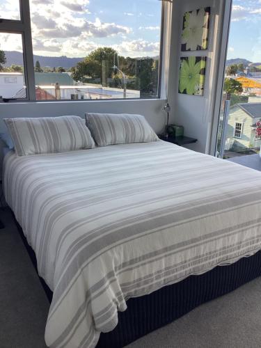 a large bed in a bedroom with a large window at Harbourview Penthouse Apartment in Whitianga