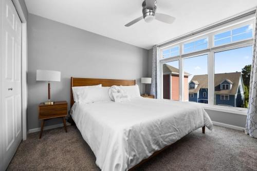 a white bedroom with a large bed and a window at Midcentury Getaway: Walk to Everything! in Traverse City