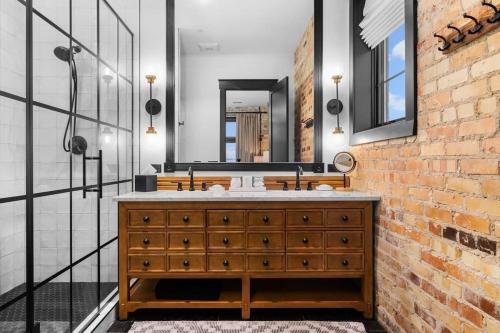 a bathroom with a wooden dresser and a brick wall at Luxury TC Loft: Historic Condo! in Traverse City