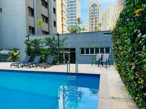 a swimming pool in a city with chairs and buildings at AV Paulista - SP - Centro in São Paulo