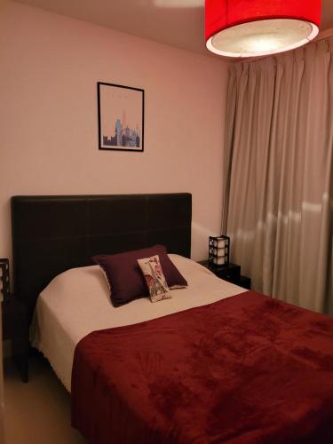 a bedroom with a large bed with a red blanket at Departamento morderno y centrico-Paseo Plaza in Navarro