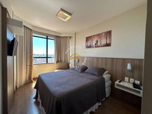 a hotel room with a bed and a large window at Excelente Flat Loft Mobiliado no Centro de Campinas !!! in Campinas