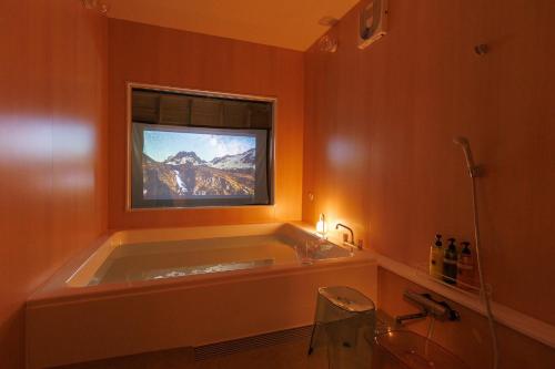 a bathroom with a tub with a television in a window at Morethan Paradise in Nagatoro