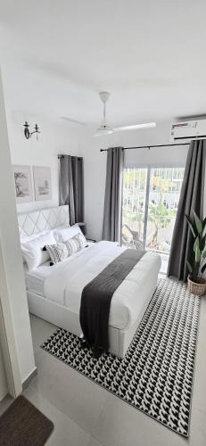 a white bedroom with a large bed and a window at Nala Host - 2BR Garden Home in Hulhumale