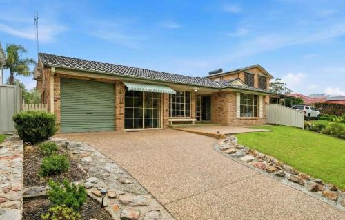 a house with a green garage and a yard at Peace by the Beach by Experience Jervis Bay in Vincentia