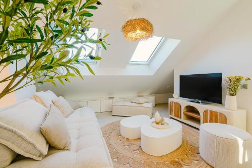 a living room with a white couch and a tv at Maison Soleil Levant in Vernon