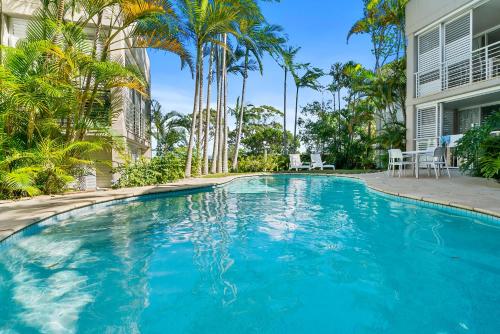 a swimming pool in front of a house with palm trees at Noosa Blue Resort in Noosa Heads