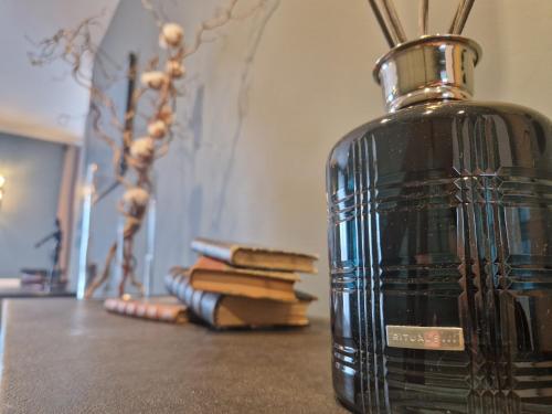 a black vase sitting on a table with books at Maison Kolsaas in Vernon
