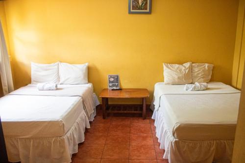 two beds in a room with a table between them at Hotel HASA in Managua