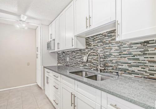 a white kitchen with a sink and a brick wall at Downtown Central Edmonton Entire Unit Condo Non Smoking in Edmonton