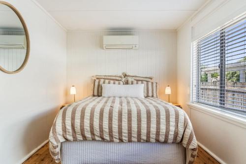 a bedroom with a bed and a mirror and a window at Selah - 36 Woodburn Street in Evans Head