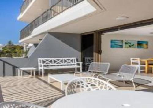 a balcony with white chairs and a table and tables at The Rocks Resort Unit 3C in Gold Coast