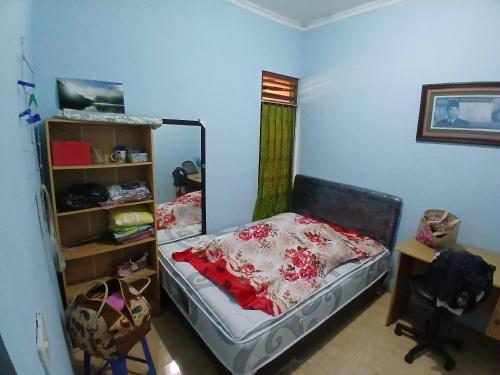 a bedroom with a bed and a desk and a shelf at Mangga in Sengkaling