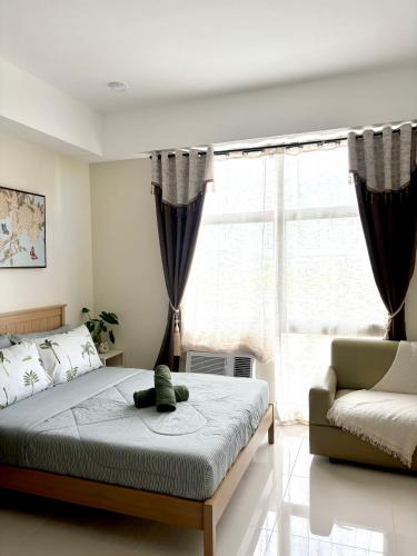 a bedroom with a bed and a couch and a window at Mactan Plains Residences in Mactan