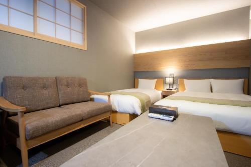 a hotel room with two beds and a couch at Fam Hotel Imaizumi in Fukuoka