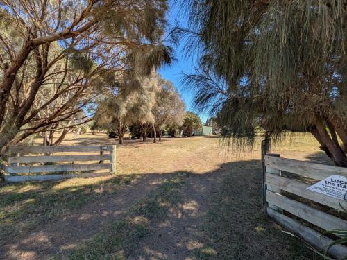 a wooden fence in a field with trees at Swallows Nest in Cape Bridgewater
