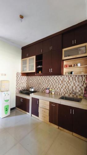 a large kitchen with brown cabinets and a sink at Homely Guest House Tegal in Tegal