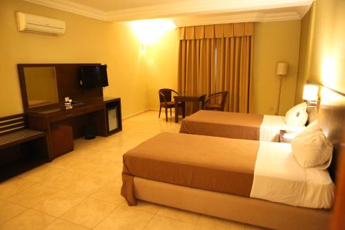 a hotel room with two beds and a television at Hotel Mauricenter Nouakchott in Nouakchott