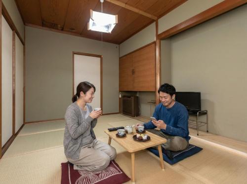 two people sitting around a table in a room at Tabist Futaba Ryokan Tatsuno in Tatsuno