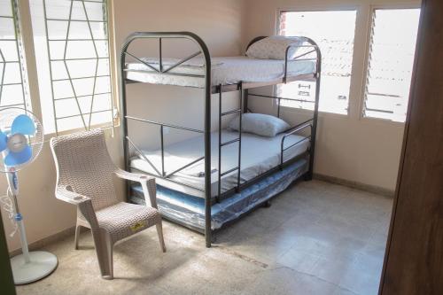 pokój z dwoma łóżkami piętrowymi i krzesłem w obiekcie Yek Hostels w mieście Santa Ana