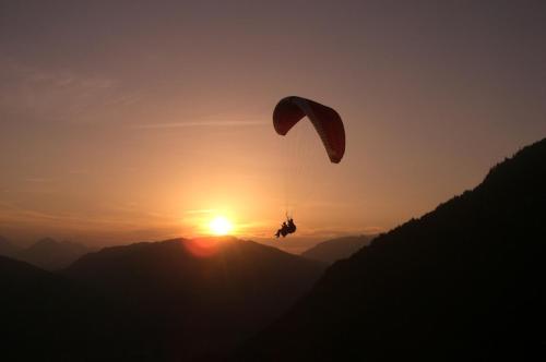 a person riding a parachute in front of the sunset at Ferienhaus Burgblick in Treffen