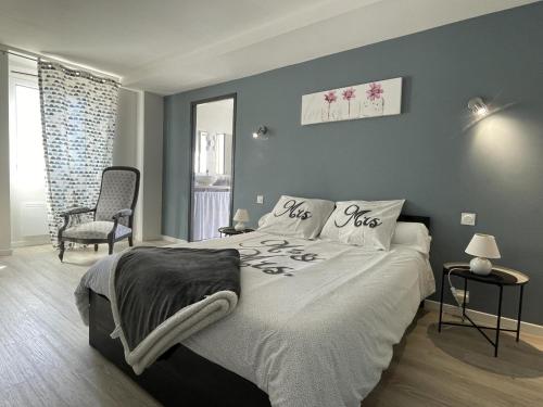 a bedroom with a large bed and a chair at Gite du coos in Audaux
