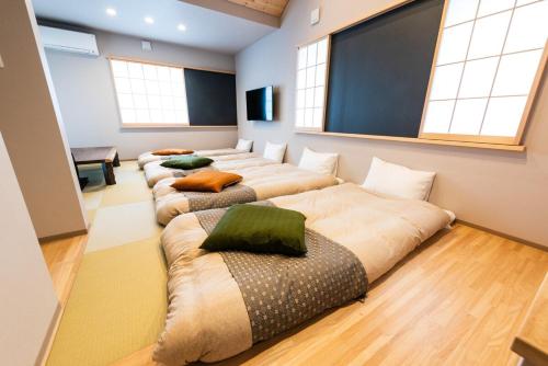 a row of beds in a room with windows at MEIBI Hakone Yumoto in Hakone