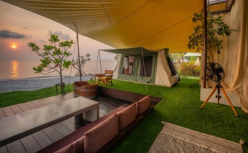 a tent with a couch and a table in the grass at Camp Cayla - COASTA in Ban Ao Makham Pom