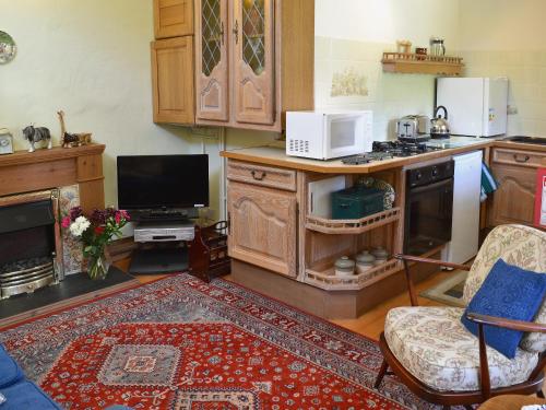 a living room with a kitchen with a stove top oven at The Stable in Hastingleigh