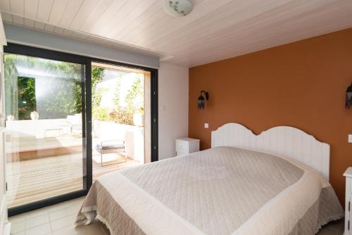 une chambre avec un grand lit et un balcon dans l'établissement ré tour de plage, à Saint-Martin-de-Ré