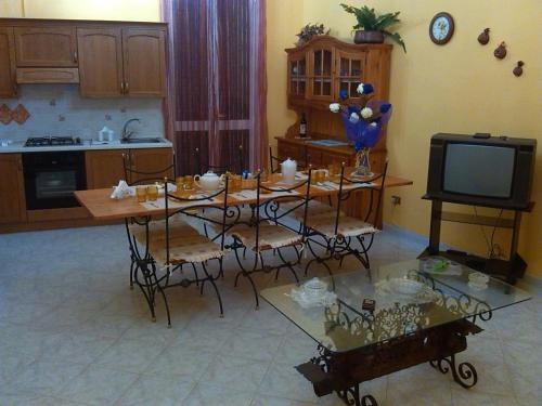 uma cozinha com uma mesa com cadeiras e uma televisão em Happy House Wifi Free Bici Free em Avola