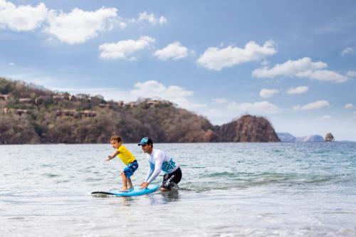 a man and a child on a surfboard in the water at Four Seasons Resort Costa Rica at Peninsula Papagayo in Culebra