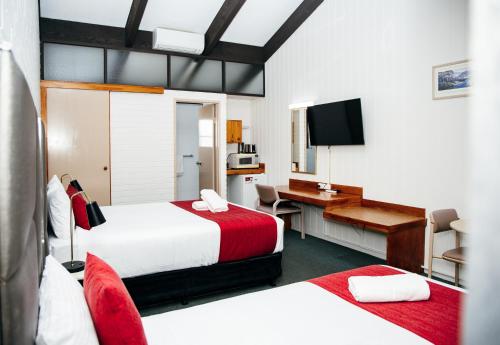 a hotel room with two beds and a desk at All Travellers Motor Inn in Coonabarabran
