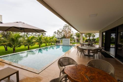 an indoor pool with tables and chairs and an umbrella at Espaço JF in Aparecida de Goiânia