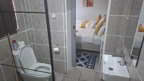 a bathroom with a toilet and a sink and a bed at Robert's Place Paarl in Paarl