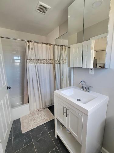 a white bathroom with a sink and a shower at Jefferson Sr - 20 mins to Manhattan, NYC in West New York