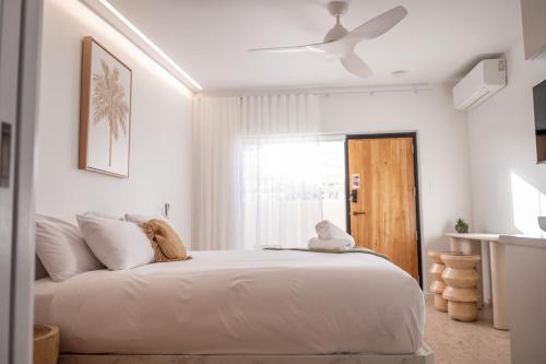 a white bedroom with a bed with a ceiling fan at Pacific Sun Bargara in Bargara