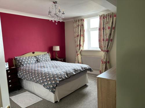 a bedroom with a bed and a purple wall at Greenmantle in Skinburness