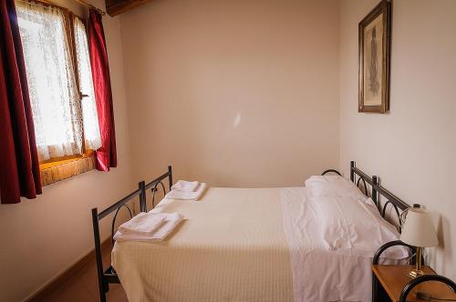 a bedroom with a bed with white sheets and a window at Agriturismo Villa Serena in Vigonovo