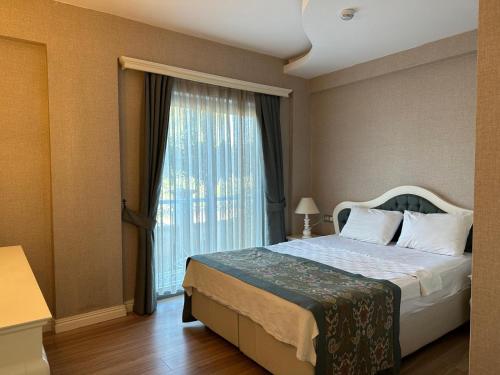 a bedroom with a bed and a large window at Defne Beach Karya in Fethiye