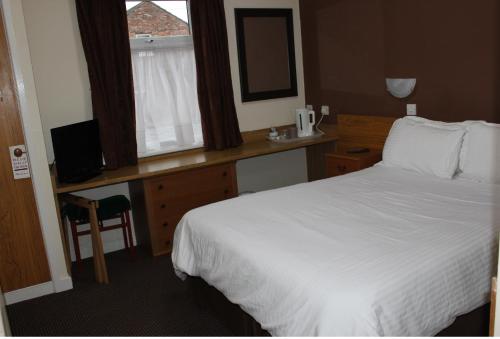 a hotel room with a bed and a desk and a window at The Premier Lodge in Morpeth