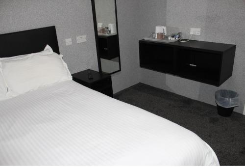 a bedroom with a white bed and a mirror at The Premier Lodge in Morpeth
