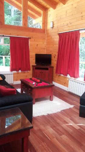 una sala de estar con cortinas rojas en una cabaña de madera en Ayelen Cabañas en Villa La Angostura