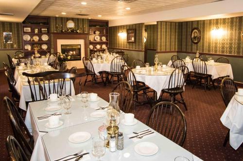 un comedor con mesas y sillas blancas en The Globe Inn, en East Greenville